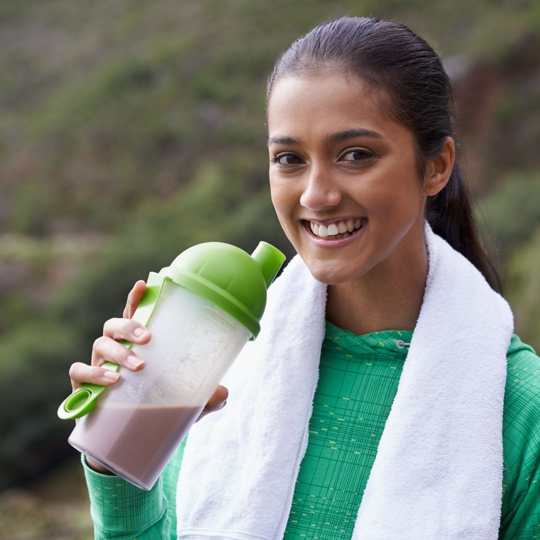 Woman holding a protein shake, smiling.